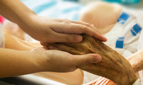 hands holding elderly hands in hospice seting