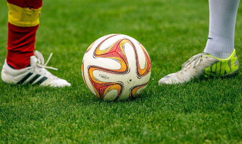 two footballers' feet with a football in between