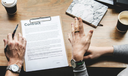 person holding pen in front of contract