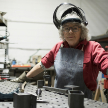 senior female welder at workbench in workshop