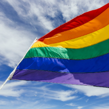 rainbow flag waving against blue sky
