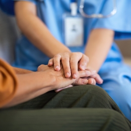 A care worker holding the hands of a patient.