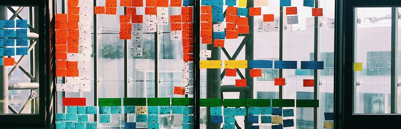 A glass board covered in post it notes with ideas on.