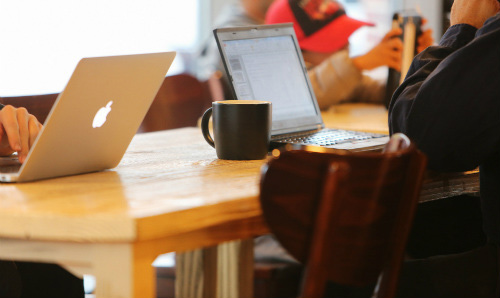 people in coffee shop writing on laptops