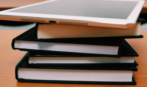 a stack of books and a tablet device on a table